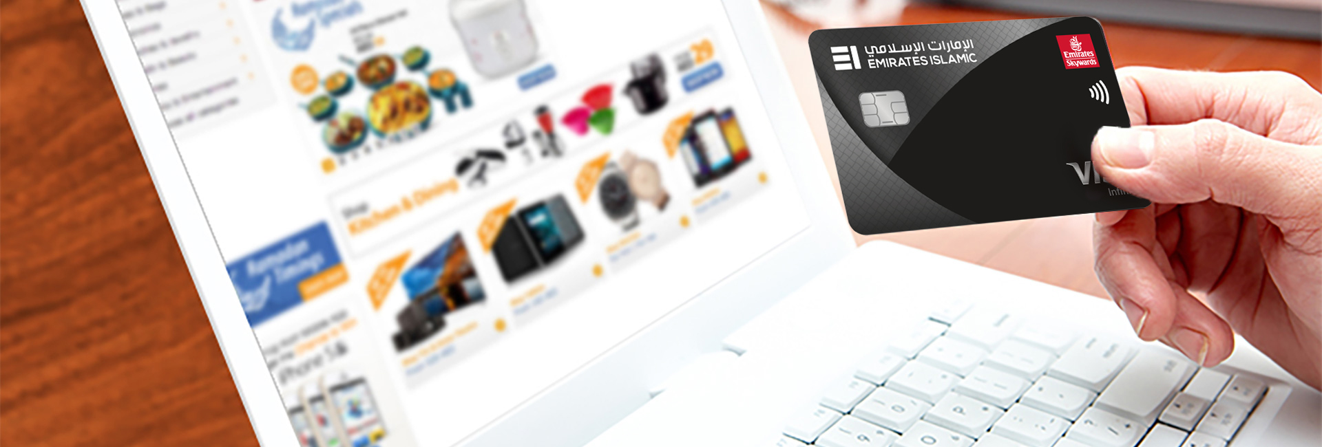 Person holding a credit card in front of a laptop