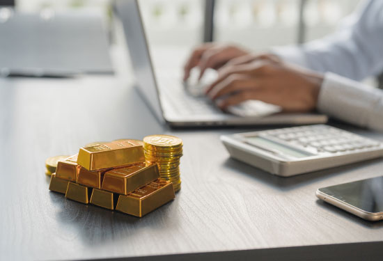 Gold bar placed on a desk near a laptop. 