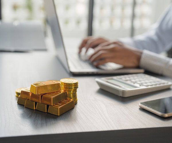 Gold bar placed on a desk near a laptop.