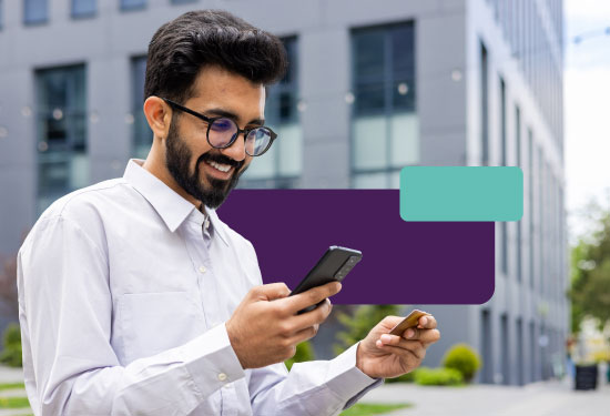 A professional in business casual attire checks their phone with a satisfied expression, with a debit card in their hand.